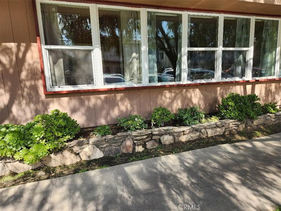Front view of a house with large windows and a small raised stone flower bed.