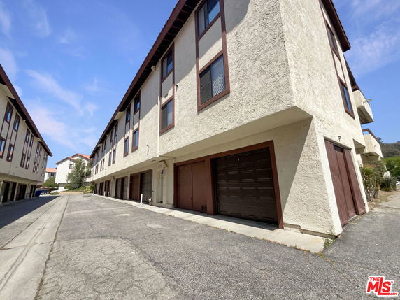 Front view of a multi-story building with garages on the ground level.