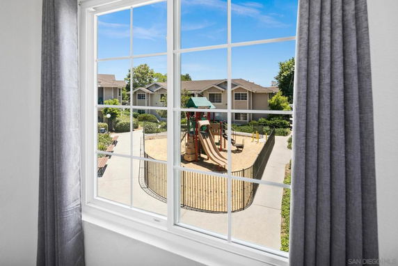 View from a window showing an outdoor playground and residential buildings.
