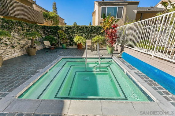 Outdoor area featuring a small rectangular swimming pool surrounded by tiled flooring and potted plants.