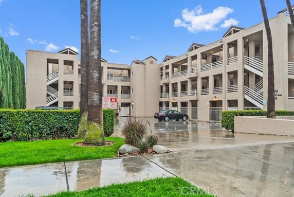 Front view of a multi-story apartment building with exterior staircases and parking area.