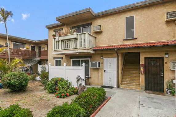 Front view of a two-story residential building with balconies and multiple entrances.