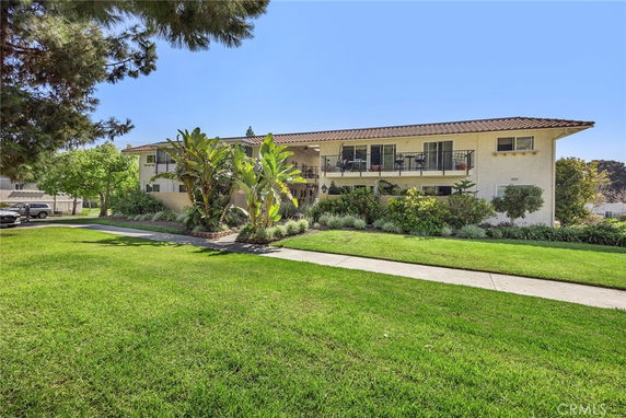 Front view of two-story residential building with balconies and landscaped garden.