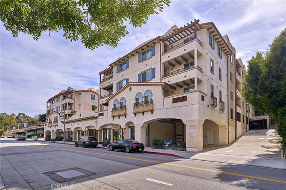 Front view of a multi-story residential building with arches and balconies.