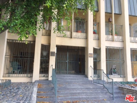 Front view of a building entrance with stairs and balcony railings.