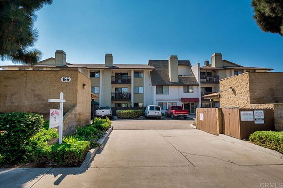 Front view of a multi-story residential building with parking area.