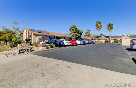 Outdoor parking area with multiple cars in front of a single-story building.