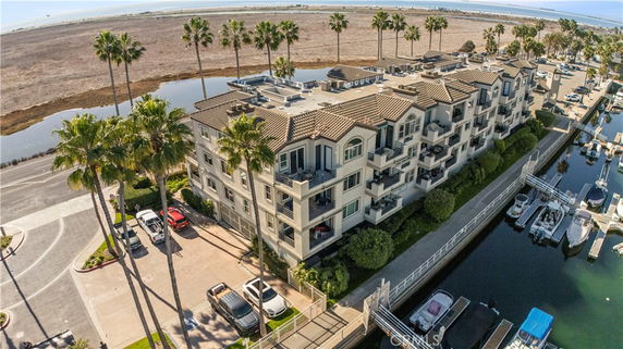 Elevated view of a multi-story waterfront building with balconies and a tiled roof.