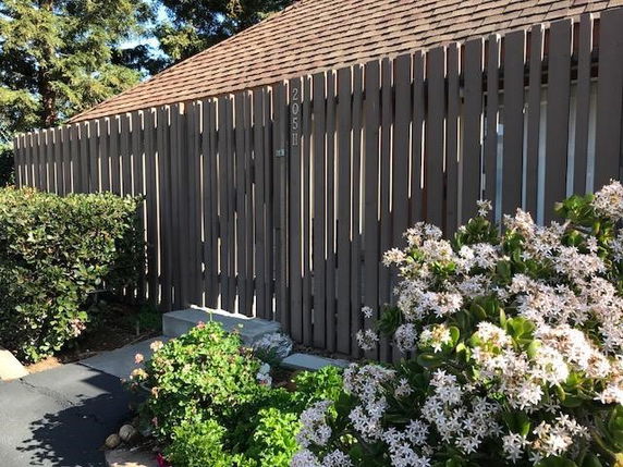 Front view of a building with a tall wooden fence and sloped roof.