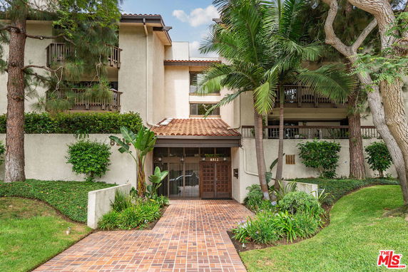 Front view of a multi-story residential building with balconies and a tiled roof entrance.
