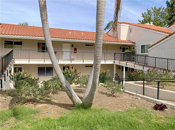 Front view of a two-story building with red-tiled roof and exterior walkways.