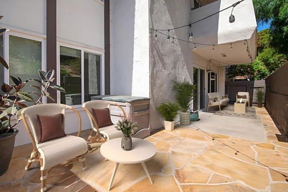 Outdoor patio area connected to a house with seating and potted plants.