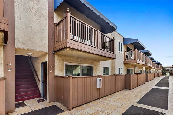 Front view of a multi-unit residential building with balconies and brown railings.