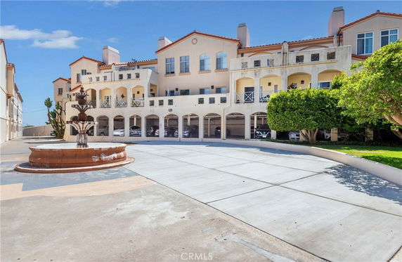 Front view of a multi-story building with arched balconies and a central courtyard with a fountain.