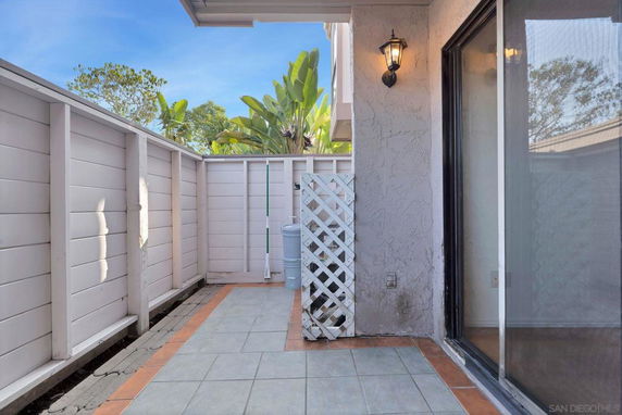 Small enclosed outdoor patio area with fence and tiled flooring.