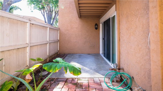 Outdoor patio area with sliding glass doors and a garden hose.