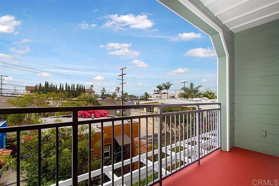 Panoramic view from a building balcony showcasing rooftops and power lines against a blue sky.