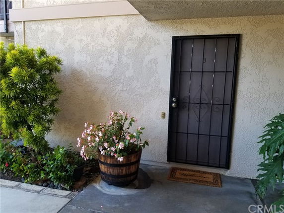 Entrance area of a building with a metal door and potted plants.