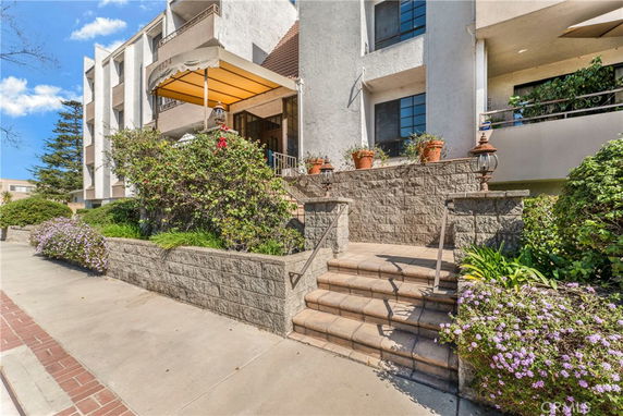 Front view of a multi-story residential building with exterior stairs and potted plants.