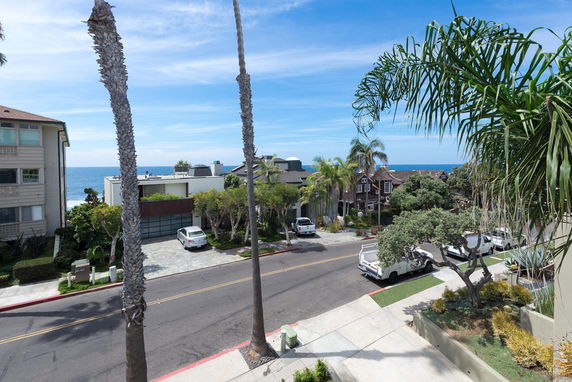 View of a residential street with several houses and the ocean in the background.