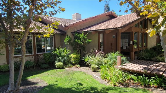 Front view of a house with a sloped tile roof and wooden entrance deck.