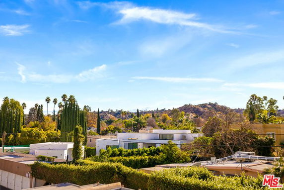 Panoramic view of surrounding residential area with hills and trees.