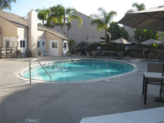 Outdoor swimming pool area with surrounding buildings and patio furniture.