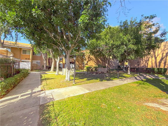 Front view of a multi-story residential building with a pathway and trees.
