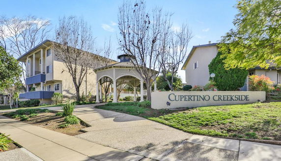 Front view of a multi-story residential building with a gazebo and sign reading Cupertino Creekside.