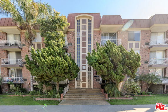 Front view of a multi-story building with a brick facade and balconies.