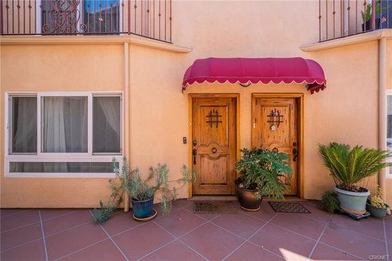 Front view of a building with double wooden doors and a red awning.