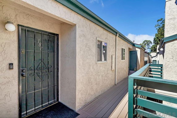 Walkway leading to the entrance of a housing unit with a metal door and a railing.