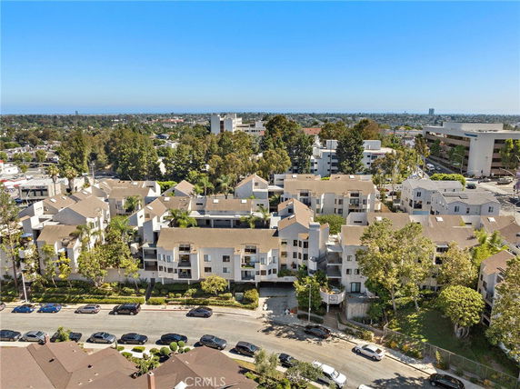 View of residential buildings and surrounding area including trees and distant cityscape.