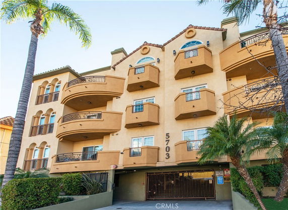 Front view of a multi-story apartment building with balconies and an arched roof.