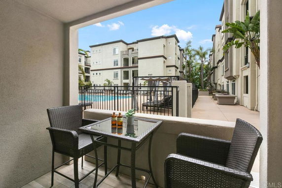 View from a patio looking at a swimming pool area and apartment buildings.