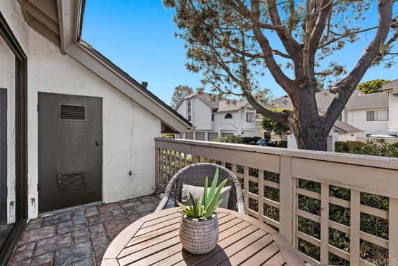 Balcony view overlooking neighboring houses and a tree.