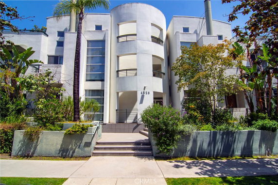 Front view of a modern multi-story building with a central round section and balconies.