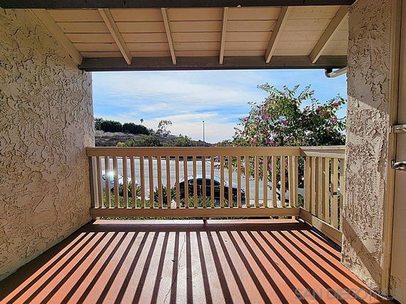 View of surrounding area from a covered balcony with railing.