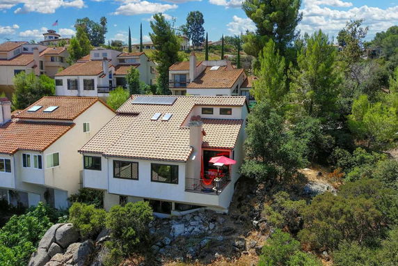 Aerial view of houses with red-tiled roofs surrounded by greenery.