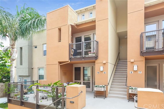 Front view of a modern multi-story townhouse with balconies and an exterior stairway.