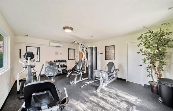Indoor gym with exercise equipment and large windows.