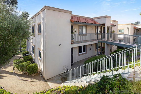 Front view of a two-story building with a walkway and greenery around it.
