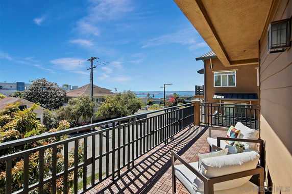 View of surrounding area from a balcony overlooking residential neighborhood and ocean.