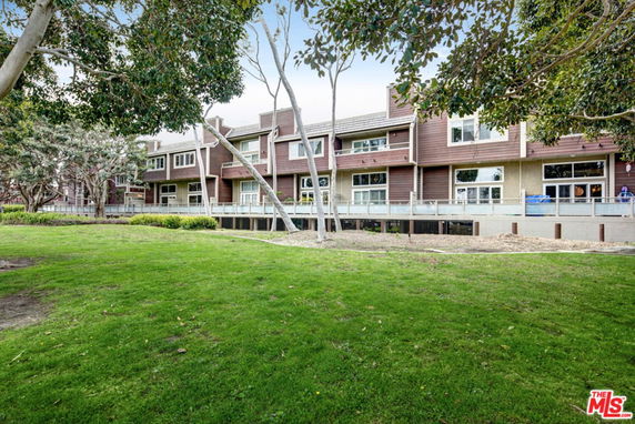 Front view of a multi-story residential building with a green lawn in front.