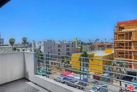 Panoramic view from a building overlooking urban surroundings with multiple buildings and clear sky.
