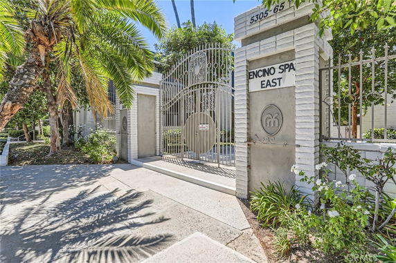 Front view of a gated building entrance with a sign reading 'Encino Spa East'.