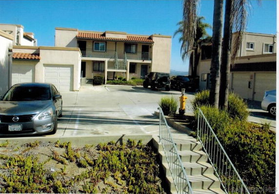 Front view of a multi-story building with garages and parking area.