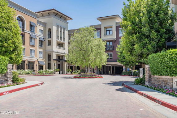 Front view of a multi-story building with a central driveway and surrounding greenery.