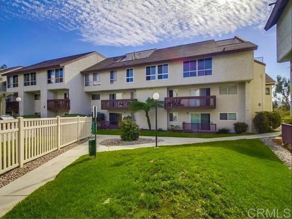 Front view of a multi-story residential building with balconies and sloped roof.
