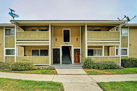 Front view of a two-story apartment building with balconies and satellite dishes.